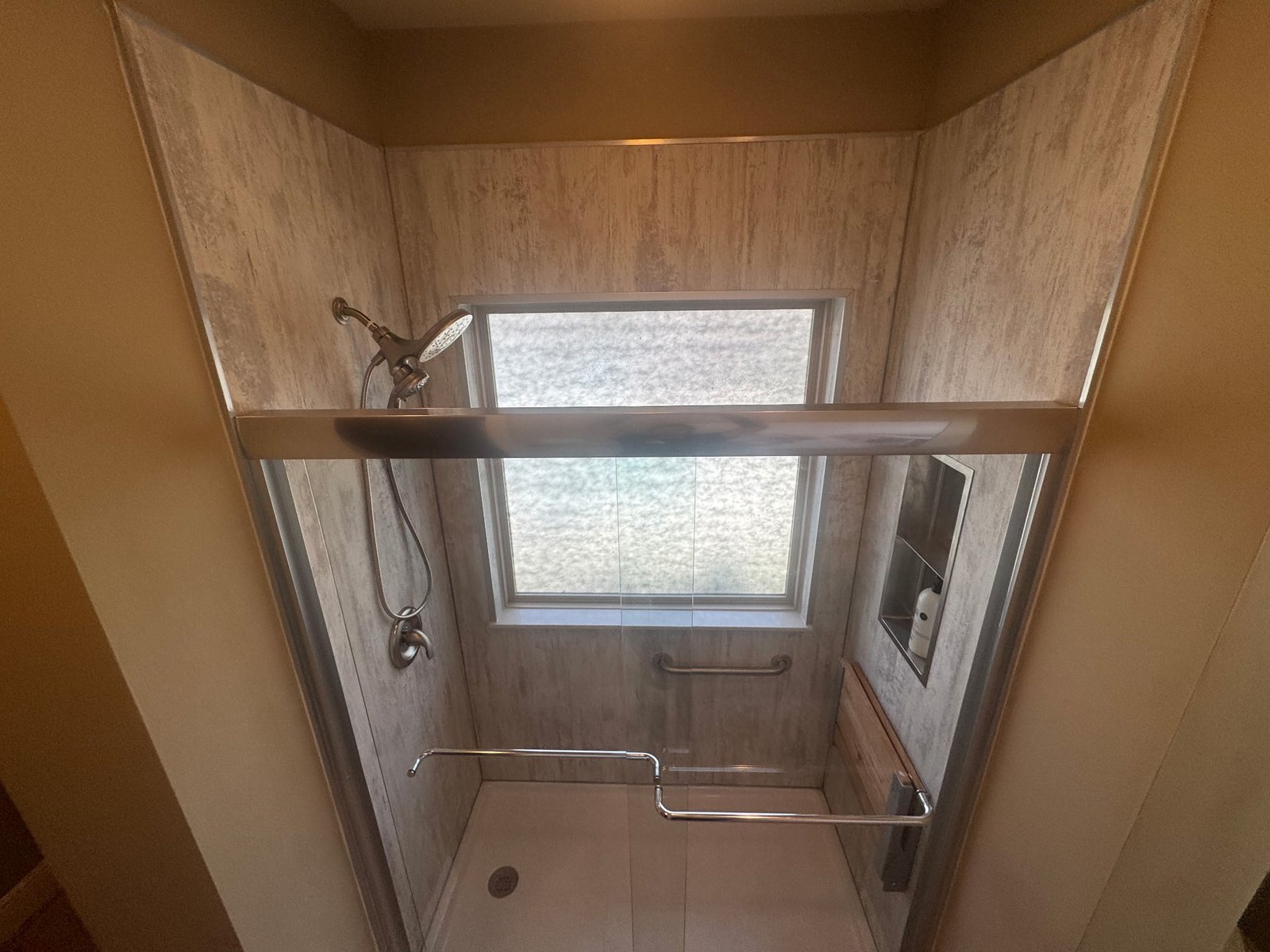 modern walk-in shower with light wood tile walls, large window with natural light, chrome fixtures, and glass enclosure demonstrating space-saving ideas